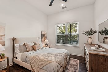 A bedroom with a bed, nightstand, and a window with blinds